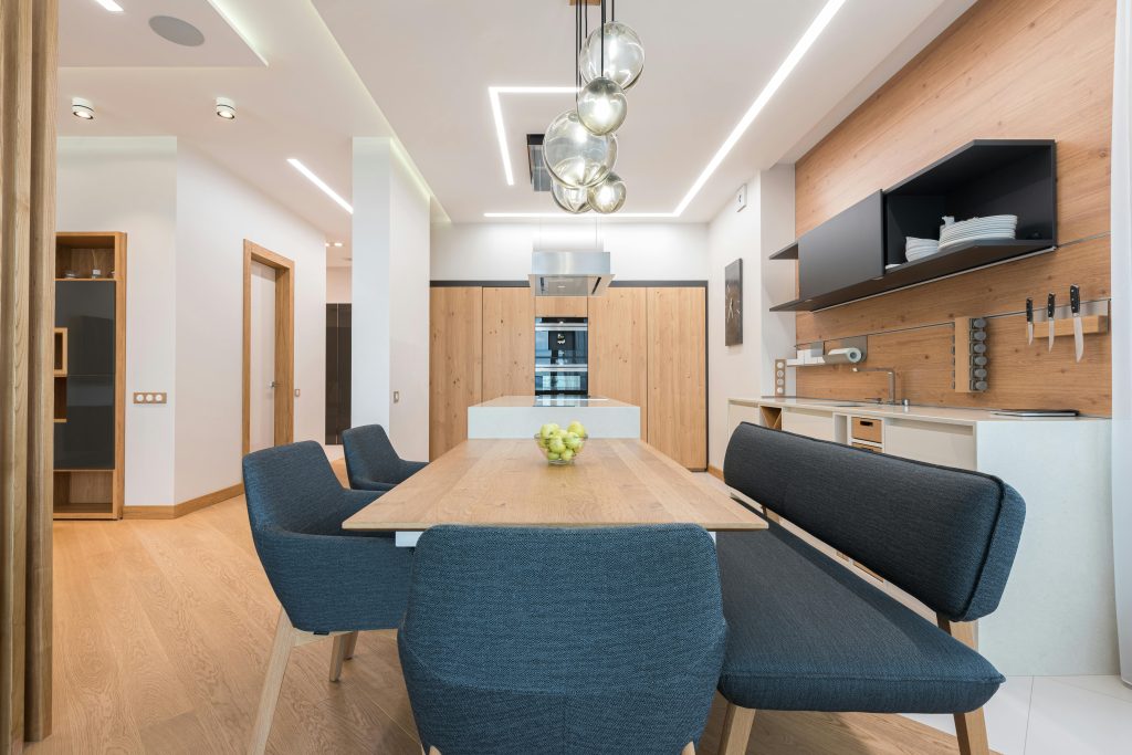 Dining zone with wooden table and soft chair and cushion placed in modern kitchen of spacious apartment